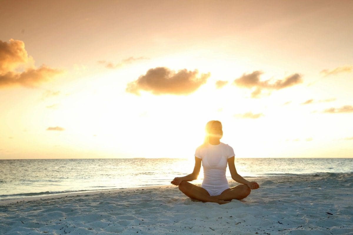 A person sitting in the sand on top of a beach.