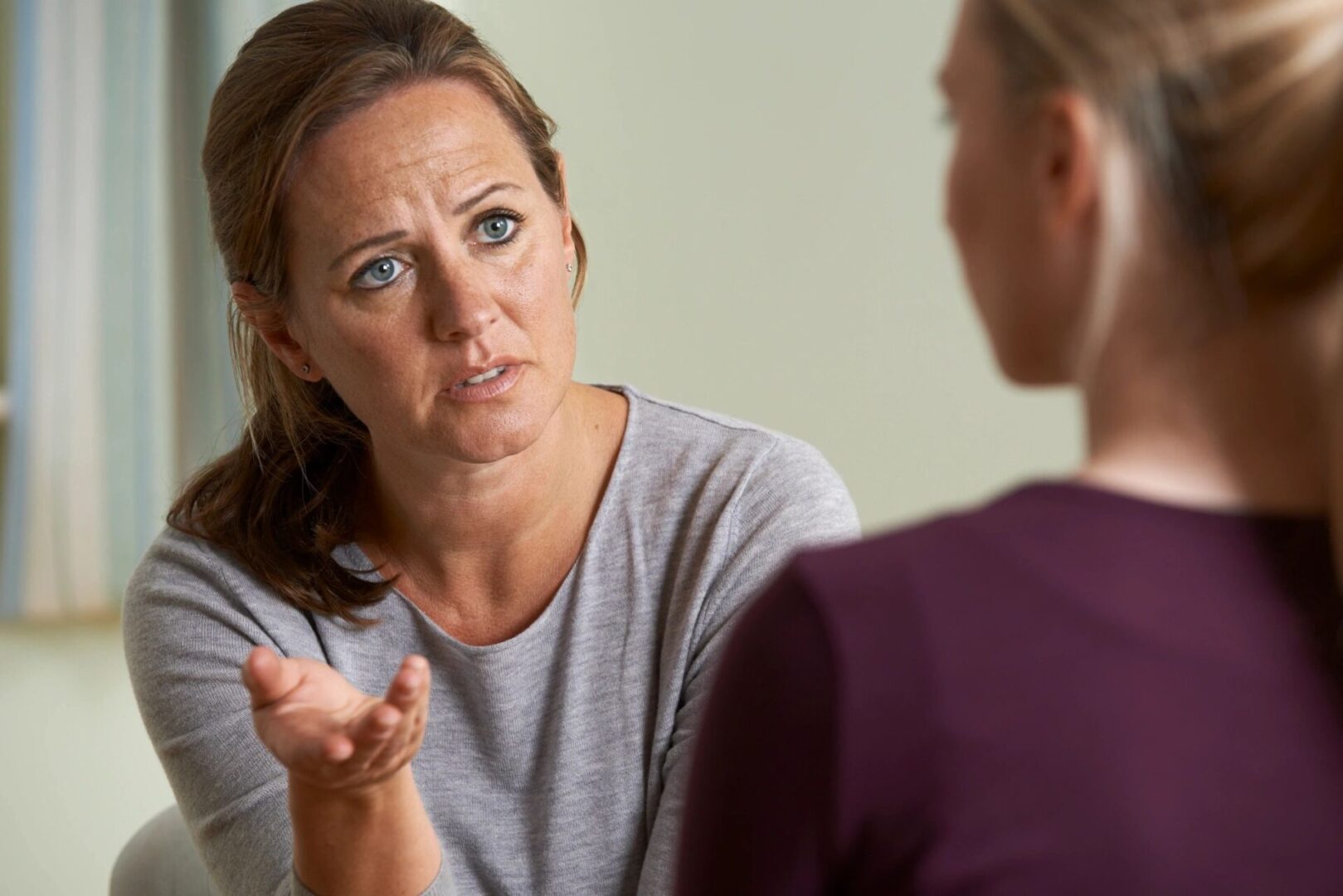 A woman talking to another person in front of a mirror.