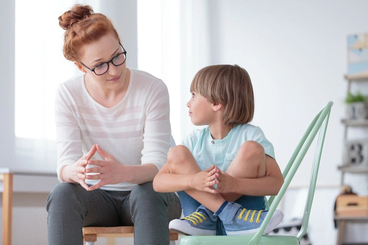 A woman and child sitting on the ground talking.